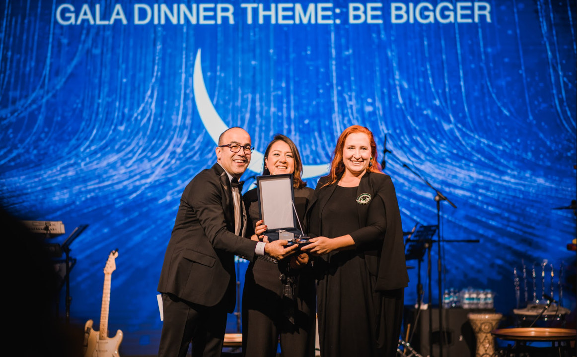 Three people on stage presenting award