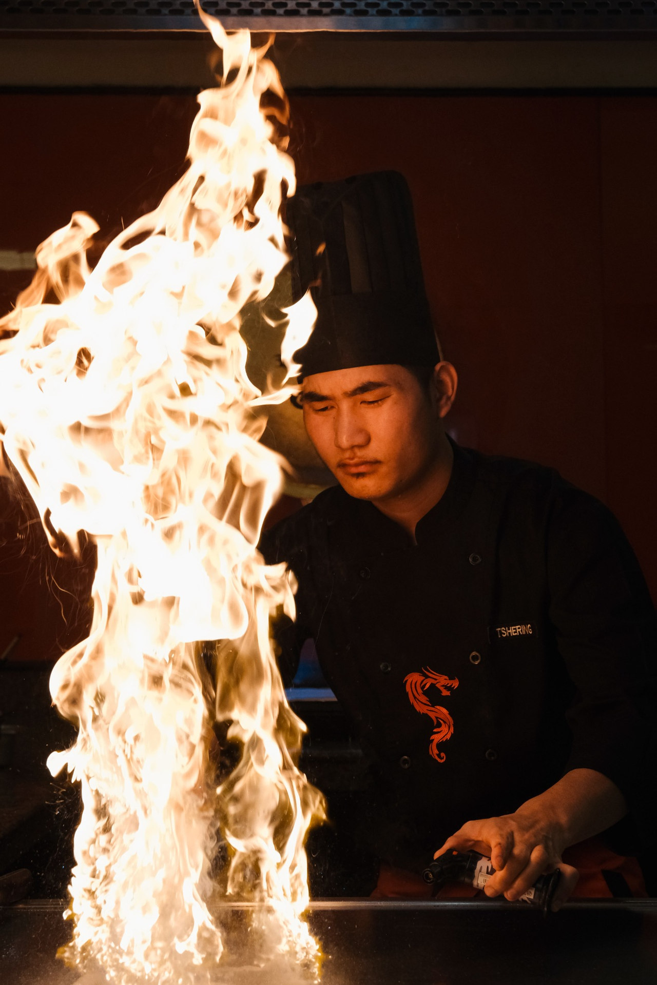 Chef working amid flames in dark kitchen