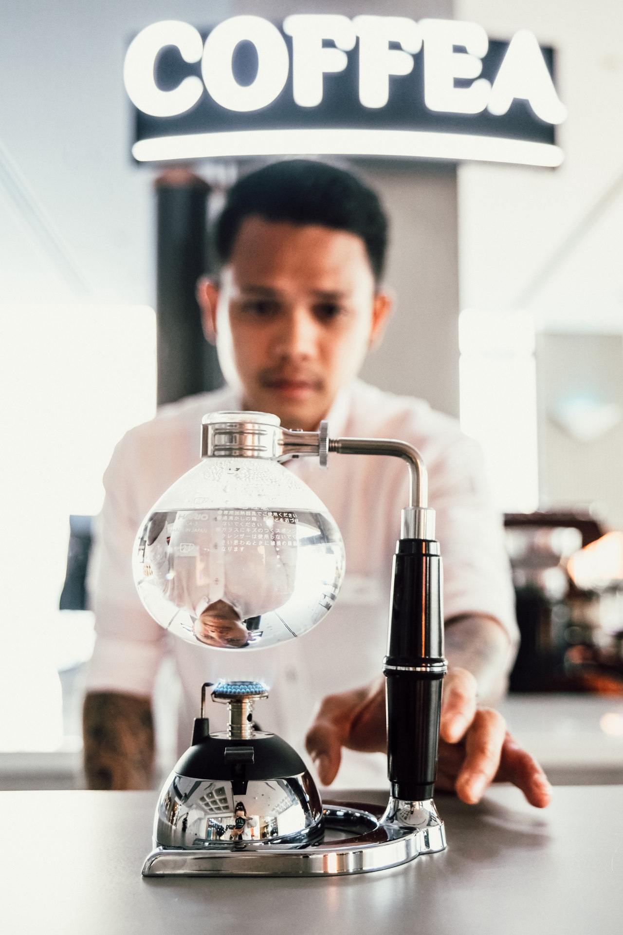 Barista brewing coffee with glass siphon