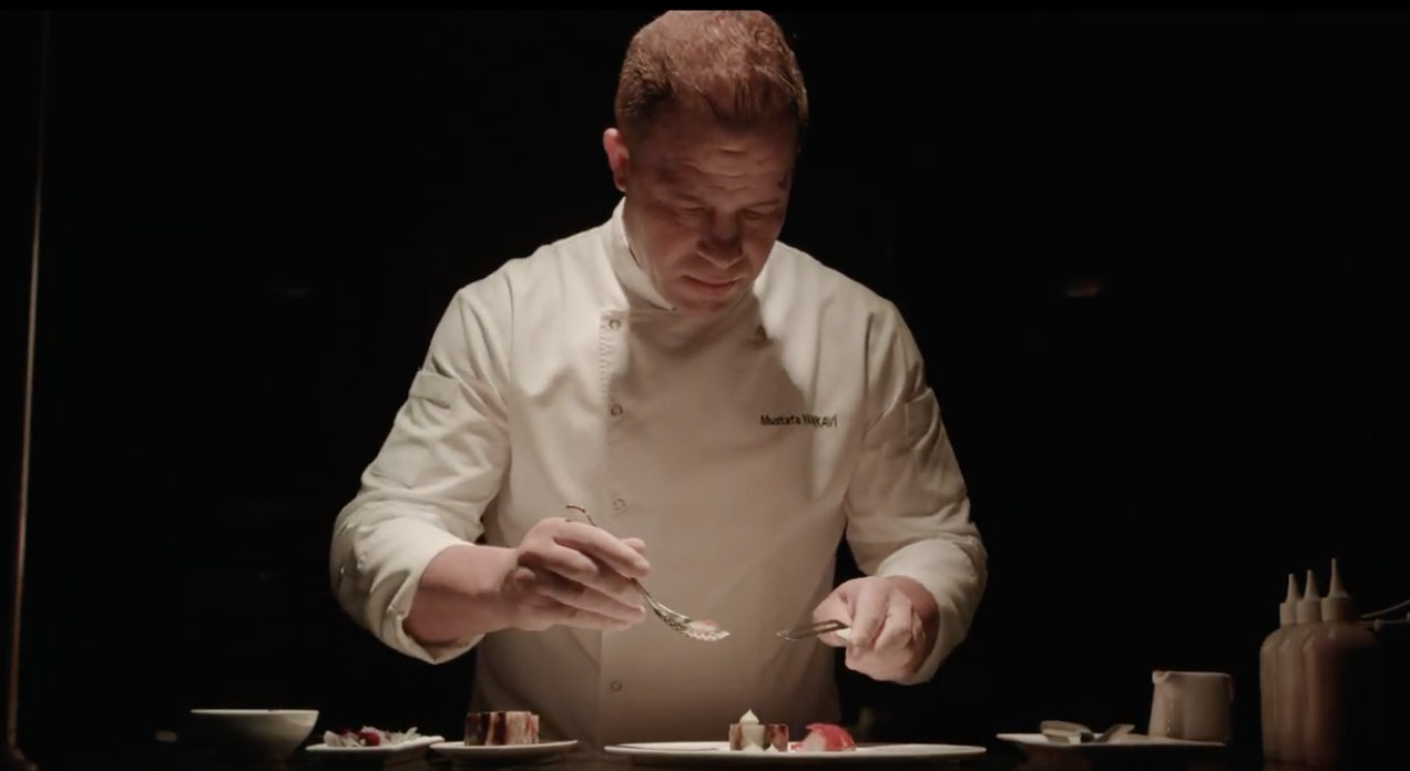 Chef plating a dish under focused light